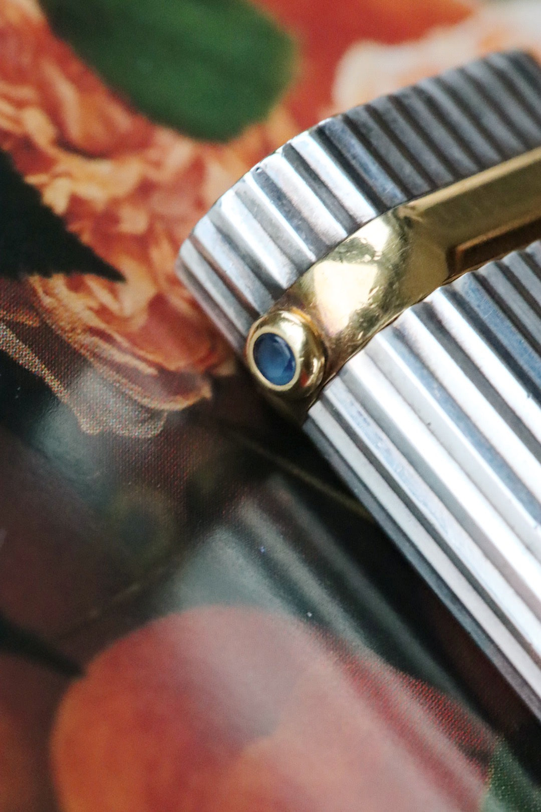 Cartier lighter with a ribbed silver finish and a blue cabochon.